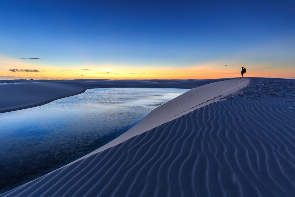 A person on the sand dunes contemplating the dusk and lagoons.
